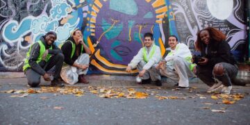 A brightly coloured mural with artists crouched beside it.