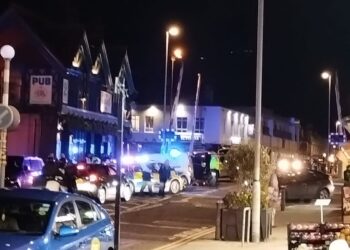Police cars with blue lights on Boundary Road, Portslade with level crossing barriers in the air.