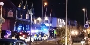 Police cars with blue lights on Boundary Road, Portslade with level crossing barriers in the air.