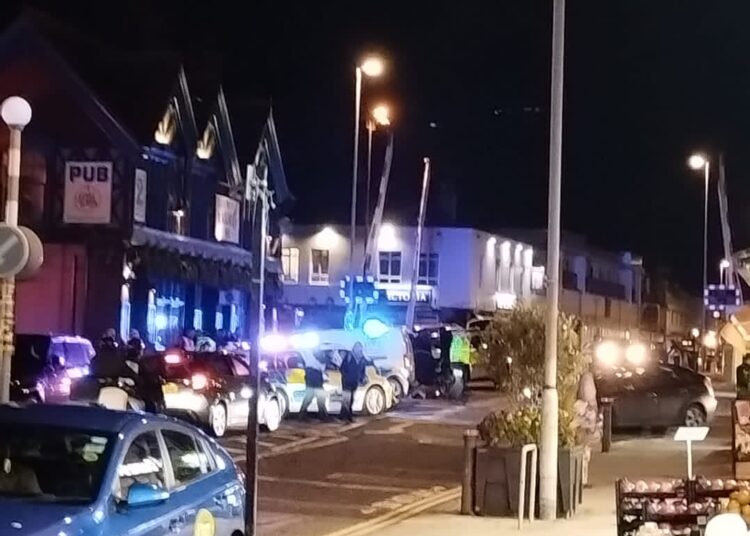 Police cars with blue lights on Boundary Road, Portslade with level crossing barriers in the air.