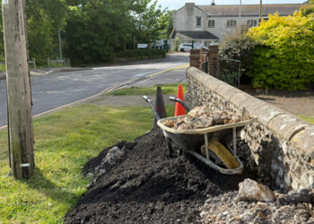 Roadworks crew left tar and rubble piled up against old flint wall