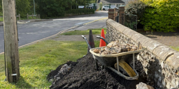 Roadworks crew left tar and rubble piled up against old flint wall